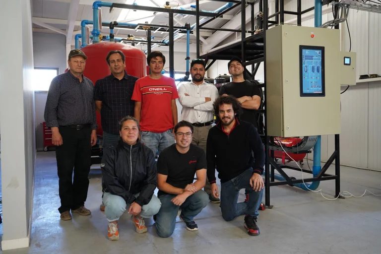 The CHEX team next to the 10 kW working unit's pressure tanks and control panel